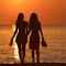 Silhouette of two lesbian girls on the beach in sunset