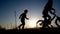 Silhouette of two little girls who play with bicycle
