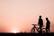 Silhouette of two man walking and biking on the walkway, exercise for health in the evening.