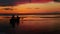 Silhouette of two men in a boat in the sea with dramatic sunset background