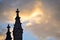 Silhouette of two pinnacles of a church and light coming from the clouds