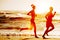 Silhouette of two running at the beach