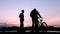 Silhouette of two teenagers communicating on the river bank or lake. Young people meet at sunrise or sunset on a bicycle and gyro.