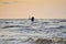 Silhouette of two unrecognizable persons standing on Mangalsala pier in wavy sea in sunset