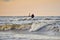 Silhouette of two unrecognizable persons standing on Mangalsala pier in wavy sea in sunset