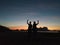 Silhouette of two women doing love sign on the beach.