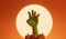 Silhouette of an undead zombie hand reaching out with a bright moon behind. 3D Rendering