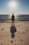 Silhouette of unknown man standing on beach. Loneliness and solitude concept. Men silhouette on sea and clear blue sky background.