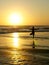 Silhouette of unknown unrecognizable woman standing on beach sea water practicing yoga and meditation looking to the sun on the ho