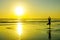 Silhouette of unknown unrecognizable woman standing on beach sea water practicing yoga and meditation looking to the sun on the ho