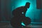 Silhouette of an unrecognizable boxer man lifting weights in a dark gym. Male athlete working out in preparation for his