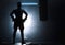 Silhouette of an unrecognizable boxer man sparring with a punching bag in a dark gym. Male athlete working out in