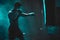 Silhouette of an unrecognizable boxer man sparring with a punching bag in a dark gym. Male athlete working out in