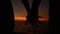 SILHOUETTE: Unrecognizable couple holds hands near picturesque ocean at sunrise.