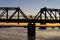 In silhouette unrecognizable cyclist back-lit in sunrise riding across Tauranga Railway bridge