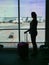 SILHOUETTE: Unrecognizable female tourist holding her bag and looking at runway.