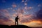 A silhouette unrecognizable guitarist playing guitar on top of a rock during sunset