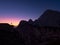 SILHOUETTE: Unrecognizable hiker faces the rocky mountain at golden sunrise.