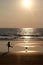 Silhouette of an unrecognizable small child kicking a footaball on a golden sandy beach at sunset