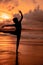 silhouette of a very slender ballerina doing ballet practice alone on the seashore with waves crashing at her