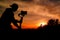 Silhouette of videographer is filming with cinema gimbal video dslr at sunset