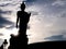 Silhouette walking buddha statue with sunlight flare