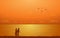 Silhouette walking couple on beach in flat icon design under sunset sky background