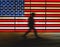 A silhouette of a walking man in front of the US flag at Times Square, NYC. Motion blur