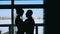 Silhouette of wedding couple embraces each other at the window