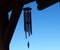 Silhouette of wind chimes against clear blue sky.