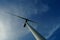 Silhouette of a wind turbine against a blue sky.