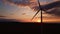 Silhouette of windmill turbine in field at sunset sky. Rotating wind generator