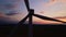 Silhouette of windmill turbine in field at sunset sky. Rotating wind generator