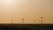 Silhouette windmills for electric power production in the meadow at sunset. Group of windmills for renewable electric