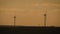 Silhouette windmills for electric power production in the meadow at sunset. Group of windmills for renewable electric