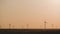 Silhouette windmills for electric power production in the meadow at sunset. Group of windmills for renewable electric