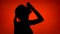 Silhouette of woman apply eye drops. Female`s face in profile put drops in eyes on red background