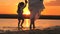 Silhouette of a woman and a child on beach at sunset. Happy family, Mom walks with child barefoot on water, joining