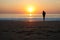 Silhouette of woman with a child in her arms on the background of sunset by the sea. Young slender girl carries a baby in the rays