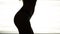 Silhouette of a woman dancing go-go on white background of bright lights