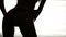 Silhouette of a woman dancing go-go on white background of bright lights