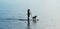 Silhouette woman and dog on standup paddleboard.