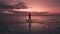 Silhouette of a woman on the evening seascape of a fantastic red sunset. A woman raises her hands and rejoices at the