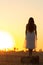 Silhouette woman figure at sunset standing on hay stack, beautiful romantic girl with long hair posing outdoors in field