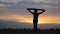 Silhouette of woman goes with raised flag of Ukraine above head on wheat field. Ukrainian lady walking with national