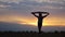 Silhouette of woman going with raised flag of Ukraine above head on wheat field. Ukrainian lady walking with national