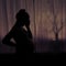 Silhouette of a woman holding her head during pregnancy. Pregnant woman in sadness at the window