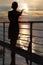 Silhouette of woman holding sun, standing on deck