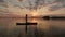 silhouette of woman on inflatable SUP board and paddling through shining water surface