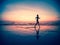 Silhouette of a woman jogger on the beach at sunset.